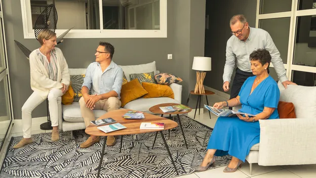 Conseillers de l’agence CISN Immobilier de Saint-Nazaire réunis dans l’espace d’accueil, consultant des brochures de logements neufs et de biens à vendre en Loire-Atlantique